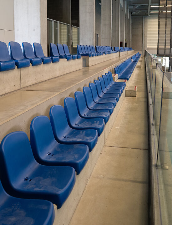 Betonnen tribune in sporthal met blauwe kuipstoelen