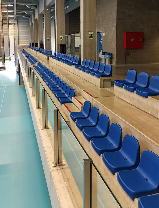 Sporthal tribune van VZW Vamos met kuipstoelen op beton